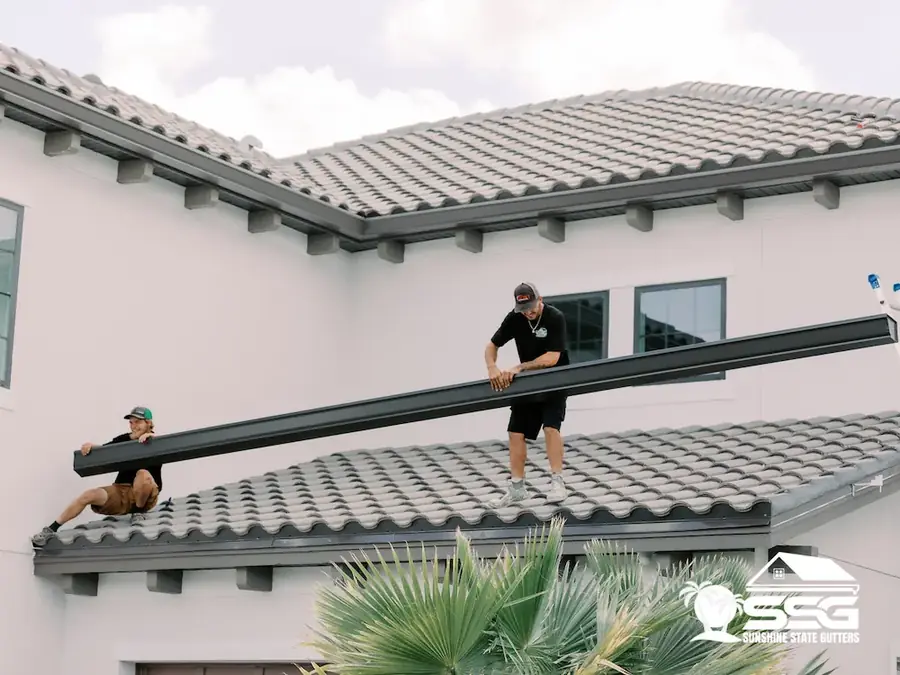Installer placing a 7-inch seamless gutter on a tile roof home